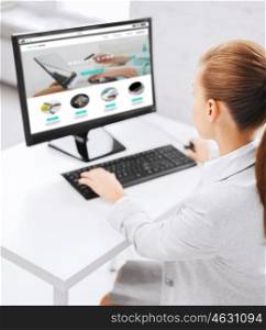 business, people, technology, internet shopping and education concept - businesswoman or student girl with online shop on computer screen sitting at office table