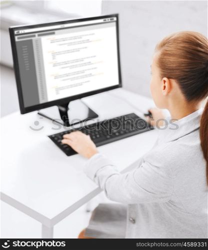 business, people, technology, programming and education concept - businesswoman or student girl with coding on computer screen sitting at office table