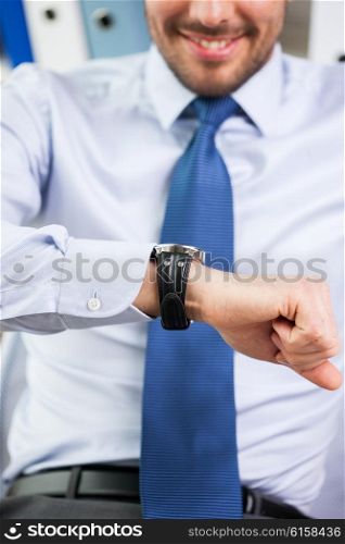 business, people, time management and work concept - close up of smiling businessman looking at his wristwatch in office