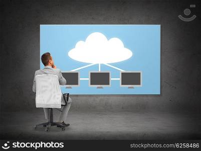 business, people, transferring data and technology concept - businessman in suit sitting in office chair over screen with cloud and server computers on gray wall background from back
