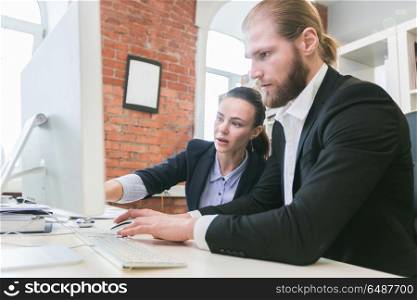 Business people using computer in office. Two business people using computer together in office pointing at monitor
