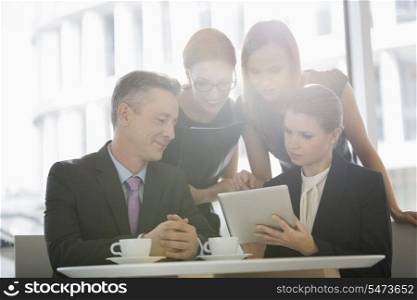 Business people using digital tablet together in office cafeteria