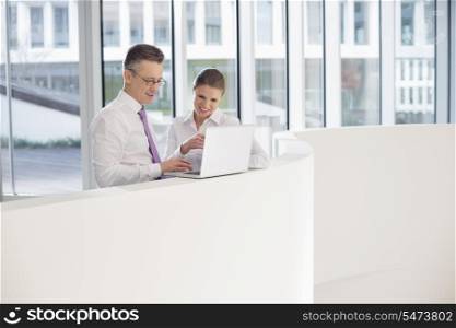 Business people using laptop on railing in office