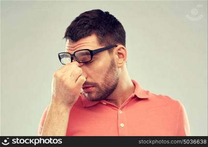 business, people, vision and overwork concept - tired man with eyeglasses touching nose bridge over gray background. tired man with eyeglasses touching nose bridge