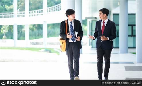 Business people walking and talking in the office building. Two confident business partners walking down in office building and talking while taking coffee.