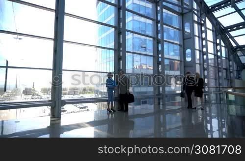 Business people walking in modern glass office building lobby