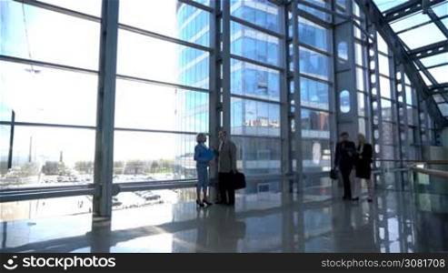 Business people walking in modern glass office building lobby