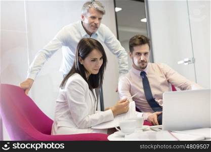 Business people watching laptop in meeting at office