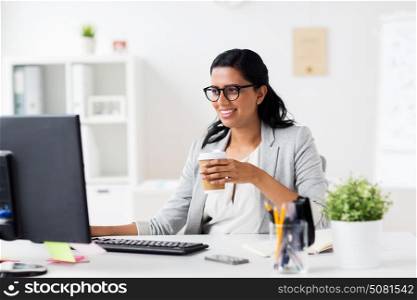 business, people, work and technology concept - happy businesswoman with computer drinking coffee from paper cup at office. businesswoman drinking coffee at office computer