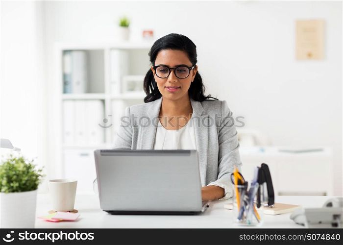 business, people, work and technology concept - happy smiling businesswoman with laptop computer at office. happy smiling businesswoman with laptop at office