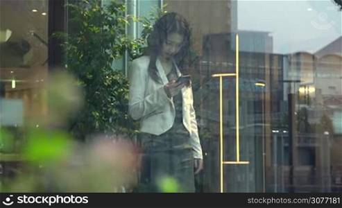 Business people working in hotel lobby, office building. Japanese female manager. Asian businesswoman, girl, woman at work, using mobile phone, telephone, smartphone for email, internet