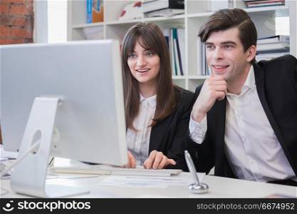 Business people working in the office. Business people working in the office, lookinf together at computer monitor and smiling