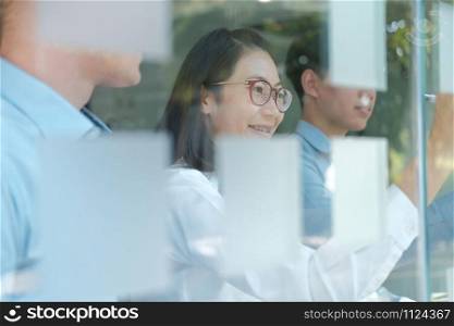 business people working planning discussing idea with sticky reminder note on glass wall at workplace