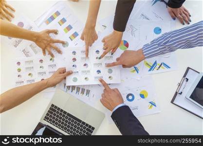 Business peoples pointing fingers to paper charts on table in meeting room. Discussion about project or job. Brainstorm for successful business concept.