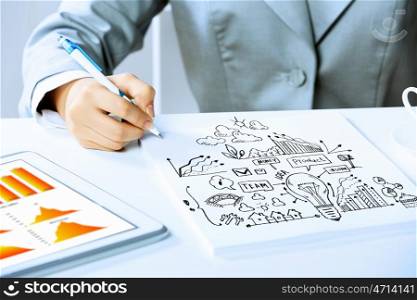 Business person at work. Image of businesswoman sitting at table and drawing sketch