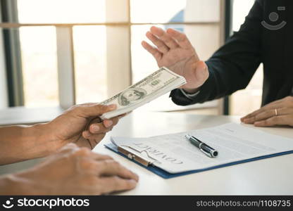 Business person refusing bribe given money by partner with anti bribery corruption concept.