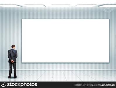 Business person standing near a blank billboard. Business person standing near a white blank billboard