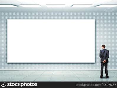 Business person standing near a white blank billboard