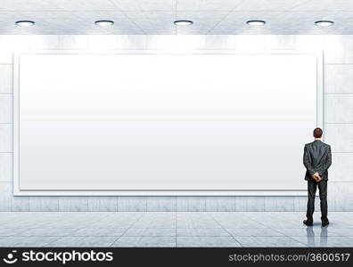 Business person standing near a white blank billboard