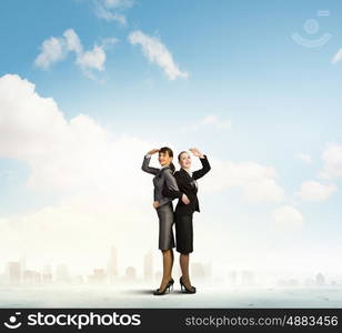 Business perspective. Image of two businesswomen looking into distance standing back to back