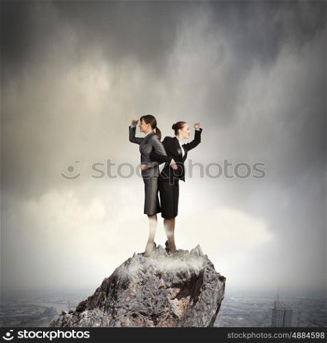 Business perspective. Image of two businesswomen looking into distance standing back to back