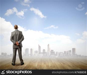 Business perspective. Rear view of businessman looking at city from distance