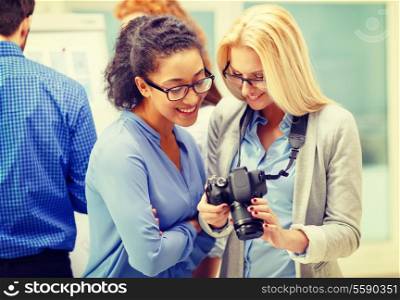 business, photography and startup concept - two smiling young women looking at digital camera at office