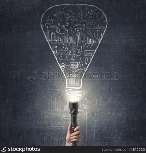 Business plan and strategy. Close up of human hand with lantern and business sketches on wall