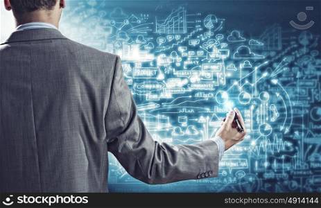 Business plan. Businessman standing with back against media screen