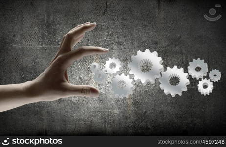 Business plan. Close up of businesswoman hand and cogwheel mechanism