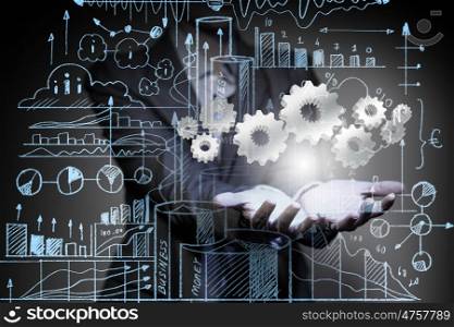 Business plan. Close up of businesswoman holding gears in hand