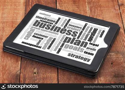 business plan word cloud on a digital tablet against weathered wood