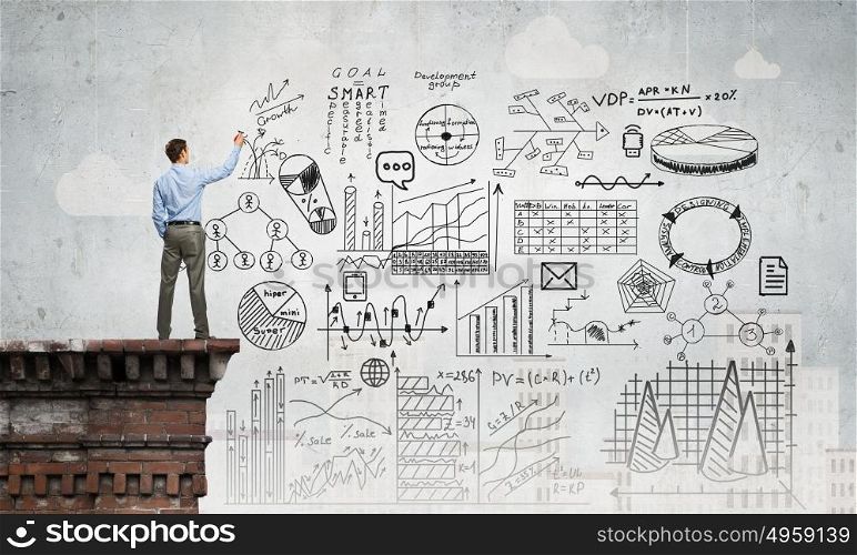 Business planning. Back view of businessman drawing plan sketches on wall