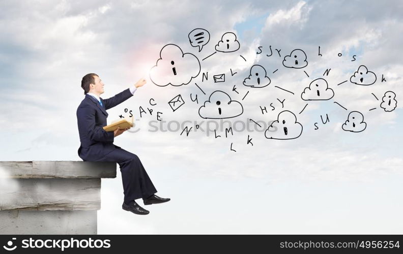 Business planning. Businessman with book sitting on top of building