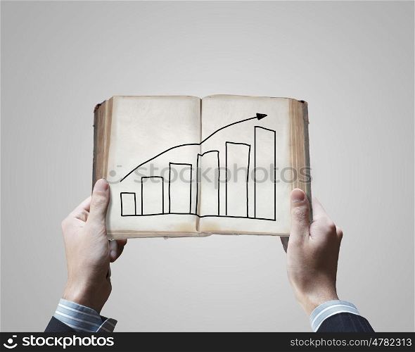 Business planning. Close up of businessman hands holding opened book with sketches