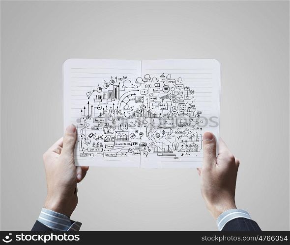 Business planning. Close up of businessman hands holding opened notepad with sketches