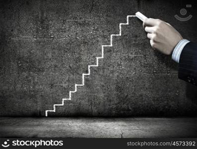 Business planning. Close up of hand drawing ladder on cement wall