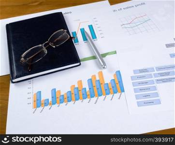 Business planning concept. Charts, notebook glasses and a ballpoint pen on the desktop. Desktop with graphic chart diary and glasses and pen