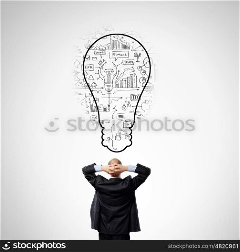 Business planning. Rear view of businessman looking thoughtfully at business sketches