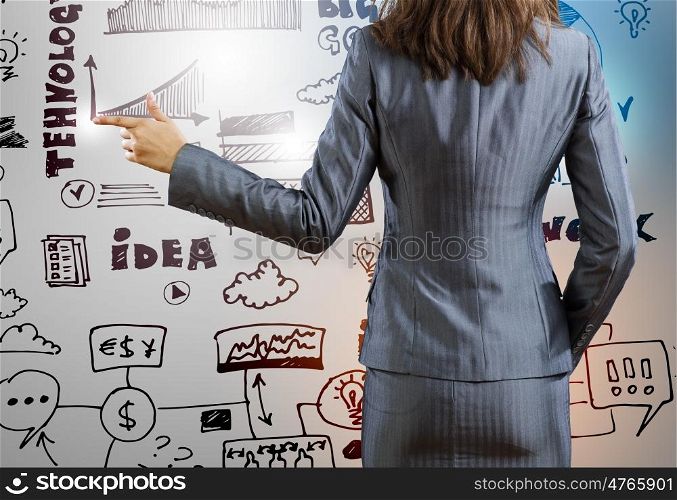 Business planning. Rear view of businesswoman and sketches at background