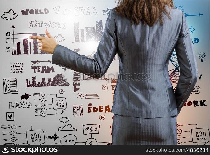 Business planning. Rear view of businesswoman and sketches at background