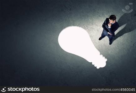 Business planning. Top view of businessman looking at bulb on floor