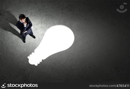Business planning. Top view of businessman looking at bulb on floor
