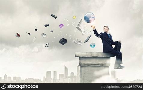 Business planning. Young successful businessman sitting on top of building