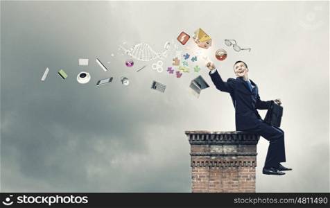 Business planning. Young successful businessman sitting on top of building