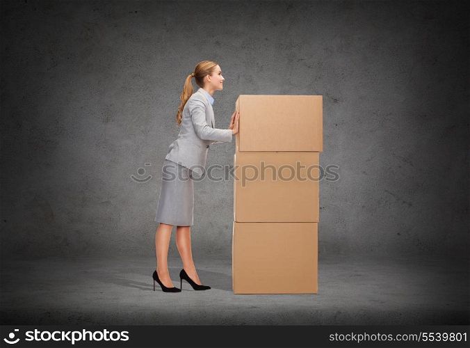 business, post and transportation concept - smiling businesswoman pushing tower of cardboards