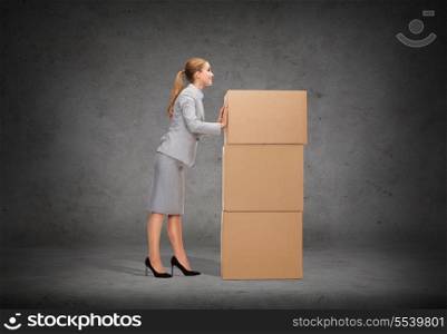 business, post and transportation concept - smiling businesswoman pushing tower of cardboards