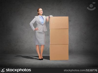 business, post and transportation concept - smiling businesswoman with tower of cardboard boxes