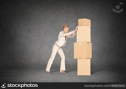 business, postal and office concept - businesswoman pushing tower of cardboard boxes