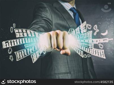Business power. Close up of businessman grasping buildings in fist